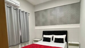 A bedroom with a bed, two bedside tables, a window with curtains, and a patterned wall above the bed. - Apartment 304 · 304 2 bedrooms - Stylish and Comfortable (Belém)