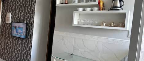 A modern kitchen with white cabinetry, a marble backsplash, and a glass-top dining table.