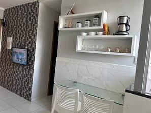 Una cocina moderna con armarios blancos, protector contra salpicaduras de mármol y una mesa de comedor con superficie de vidrio.