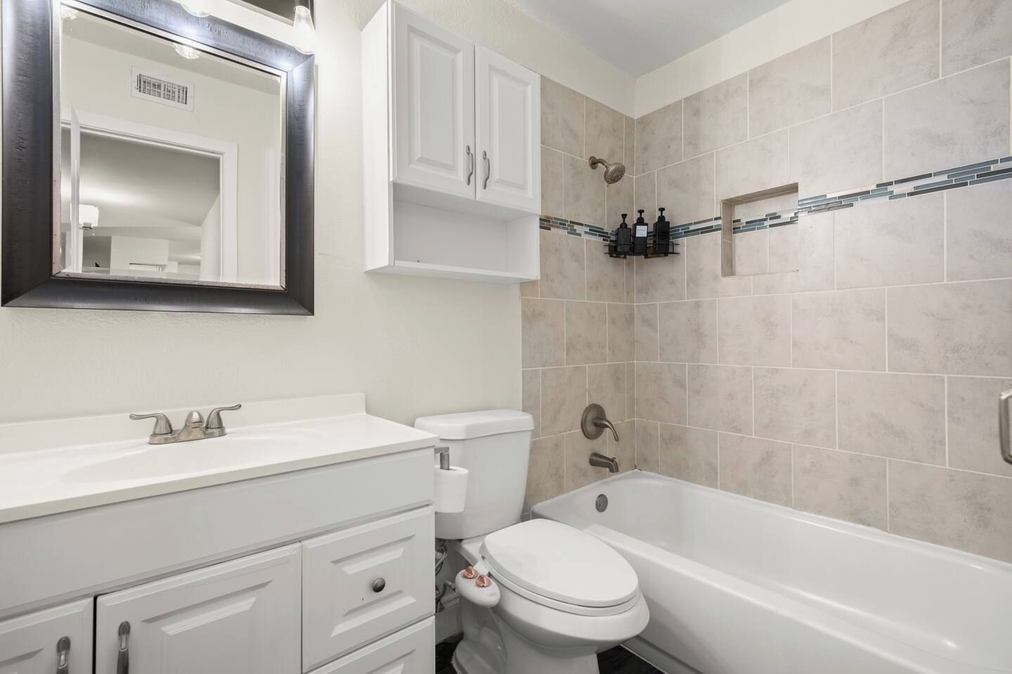 Ein Badezimmer mit weißem Waschtisch, Toilette, Badewanne und Dusche.