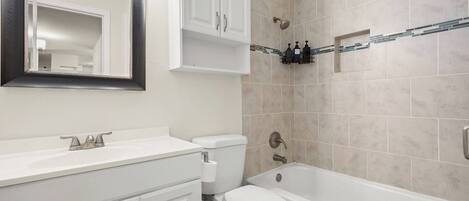 A bathroom with a white vanity, a toilet, a bathtub, and a shower.