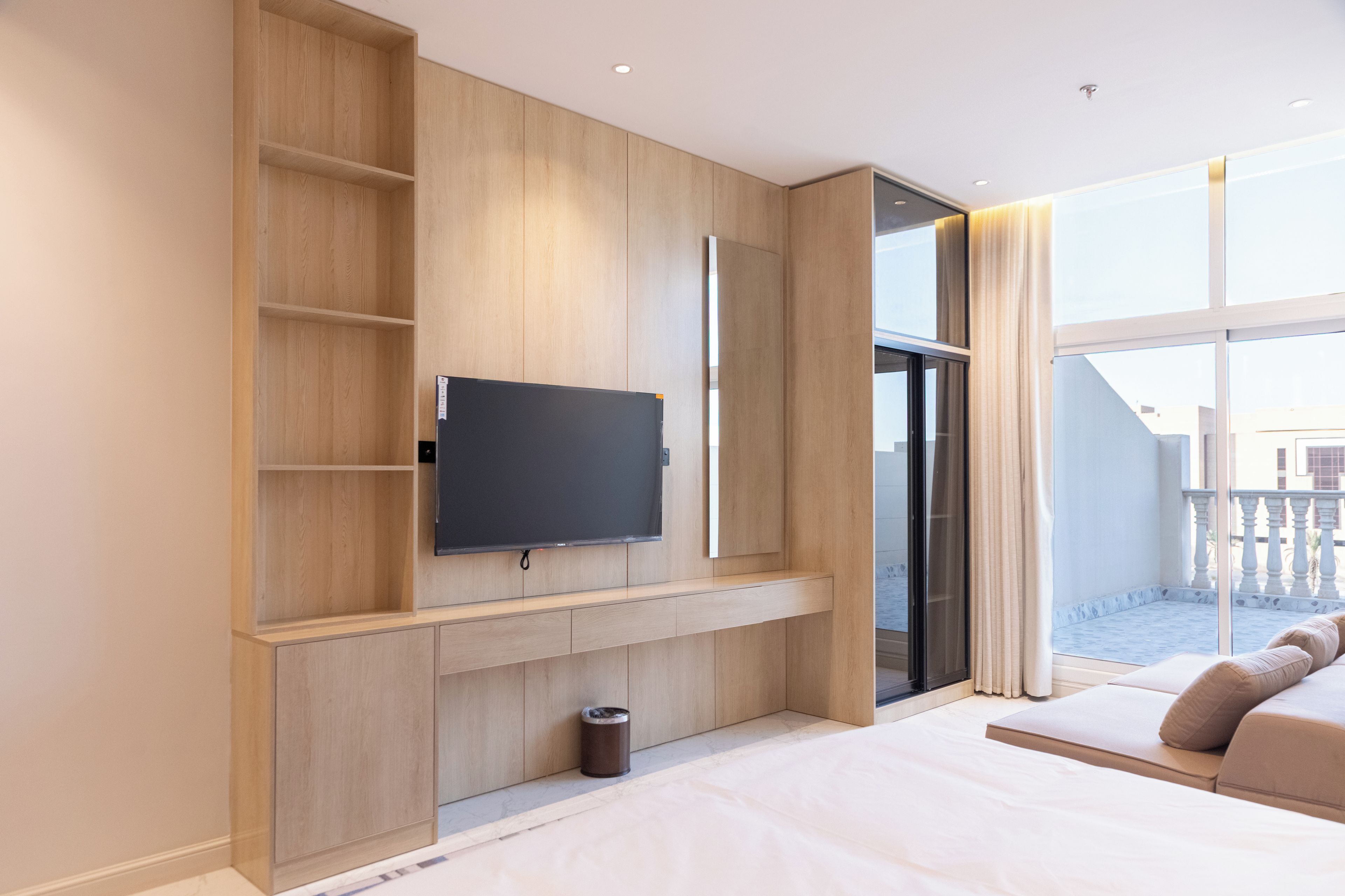 Une chambre d’hôtel moderne dotée d’un grand téléviseur à écran plat fixé sur un mur en bois, d’une petite poubelle et d’un balcon avec vue.