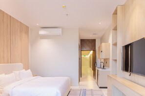 A hotel room with a bed, a flat-screen TV, a kitchenette, and a bathroom. - Olana Hotel (Riyadh)