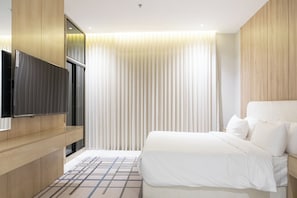 A hotel room with a bed, a TV mounted on the wall, and a window with curtains. - Olana Hotel (Riyadh)