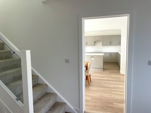 A staircase leading to a kitchen area with a dining table and chairs. - Brand New detached 3 bedroom 2 bathroom house on the edge of Epping Forest (Coopersale)