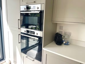 A kitchen with a built-in oven, a coffee maker, and a glass jar on the counter.