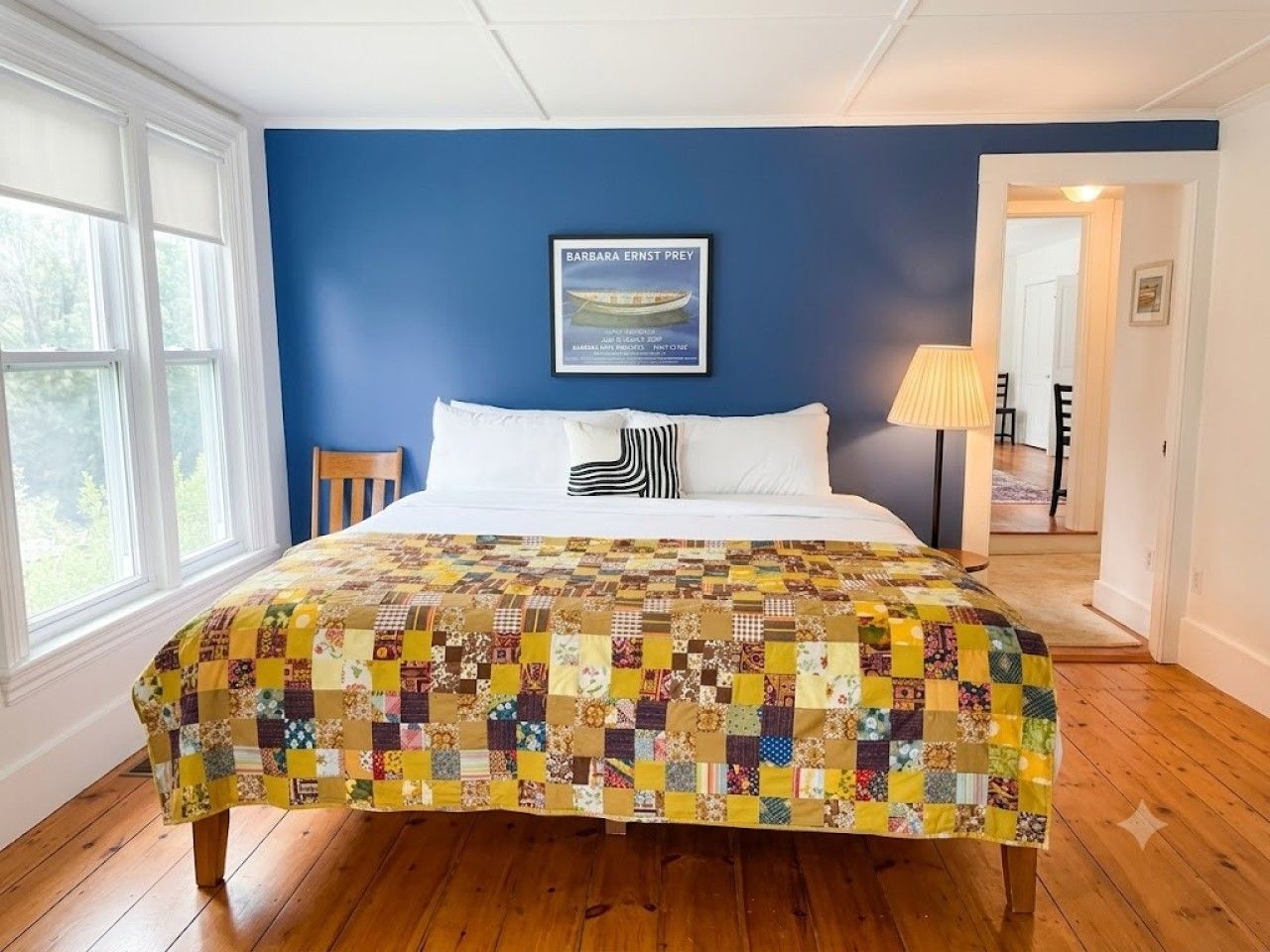 Un dormitorio con una cama grande, una pared azul y un cuadro enmarcado en la pared.