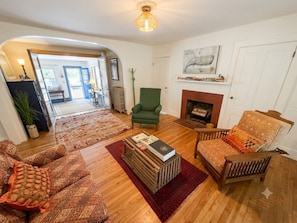 A living room with a fireplace, wooden flooring, and patterned furniture.