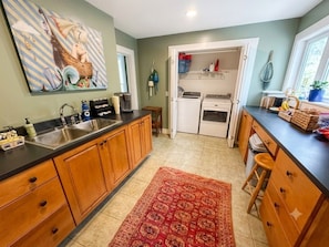 A kitchen with wooden cabinets, a red rug, and a painting on the wall. - Towne Motel Suite #1 (Camden)