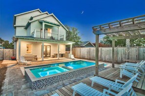 A two-story house with a swimming pool, outdoor seating, and a wooden deck. - King's Castle: Steps to Beach | Heated Pool & Spa | Golf Cart | Game Room (Destin)