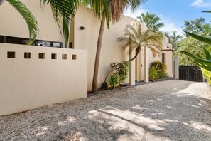 A building with a beige exterior, a gravel driveway, and a black gate. - ODS25 - Colorful Tropical Escape, Private Pool and Walk to Beach (Tamarindo)