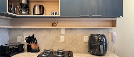 A modern kitchen with a built-in stove, coffee maker, and a kettle on the countertop.