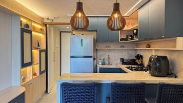 Una cucina moderna con isola centrale, due luci a sospensione e frigorifero integrato.