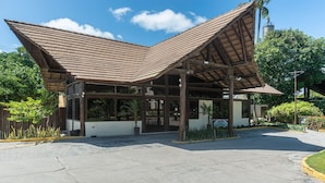 A building with a large, open entrance area and a sloped roof structure. - Nannai Residence Muro Alto Beira Mar (N. Sra. do Ó)