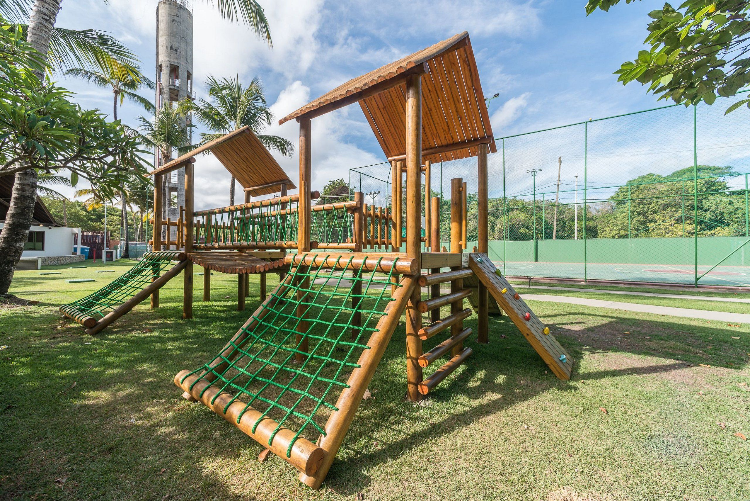 A playground with a wooden climbing structure and a slide.