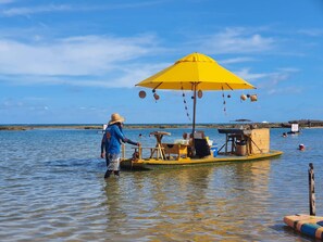 A boat with a yellow umbrella and a person standing on it. - Nannai Residence Muro Alto Beira Mar (N. Sra. do Ó)
