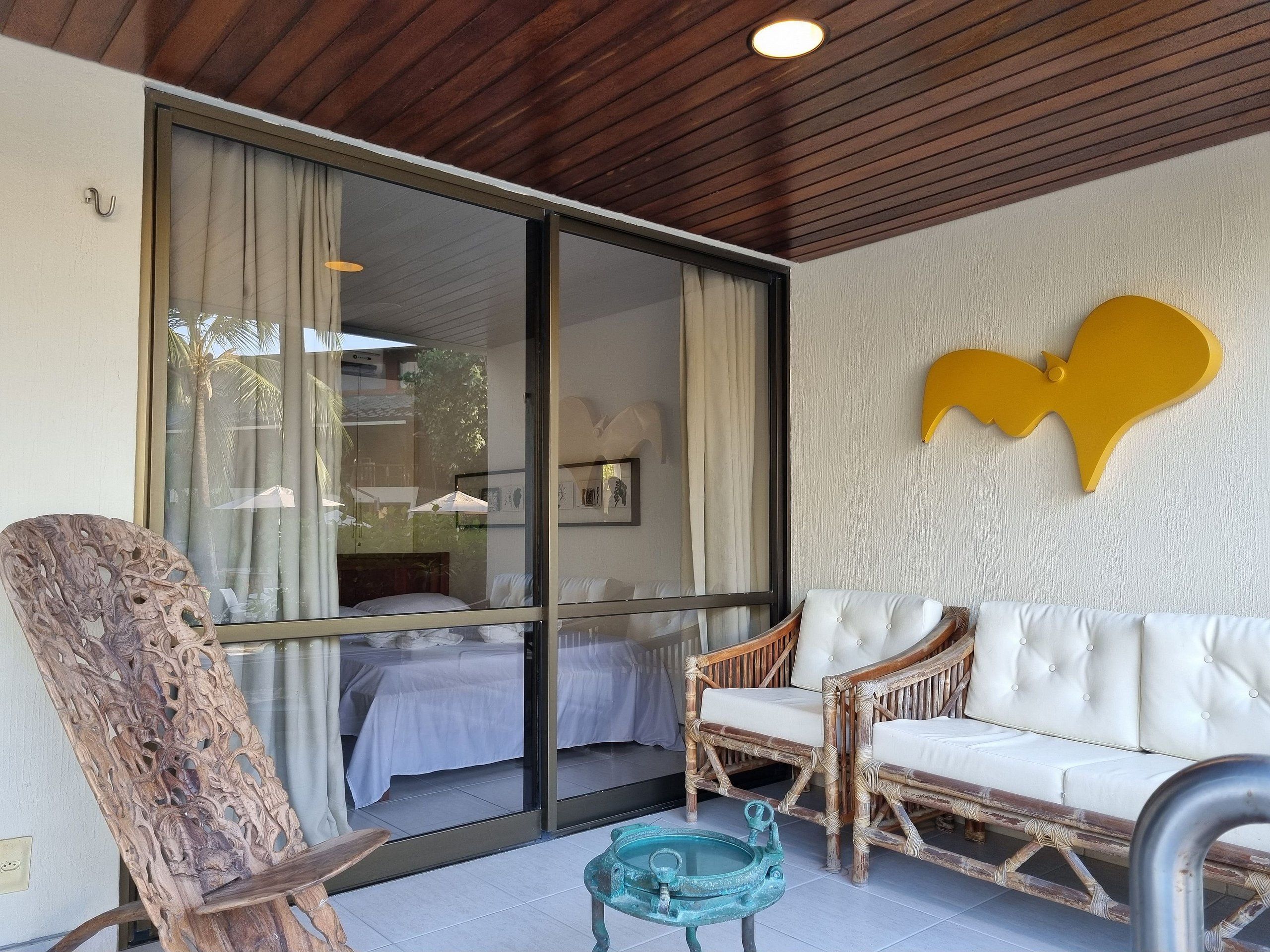 Una habitación con un gran ventanal corredero, un sofá blanco y una silla de madera.