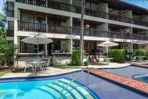 A multi-story hotel with outdoor swimming pools, lounge chairs, and umbrellas. - Nannai Residence Muro Alto Beira Mar (N. Sra. do Ó)