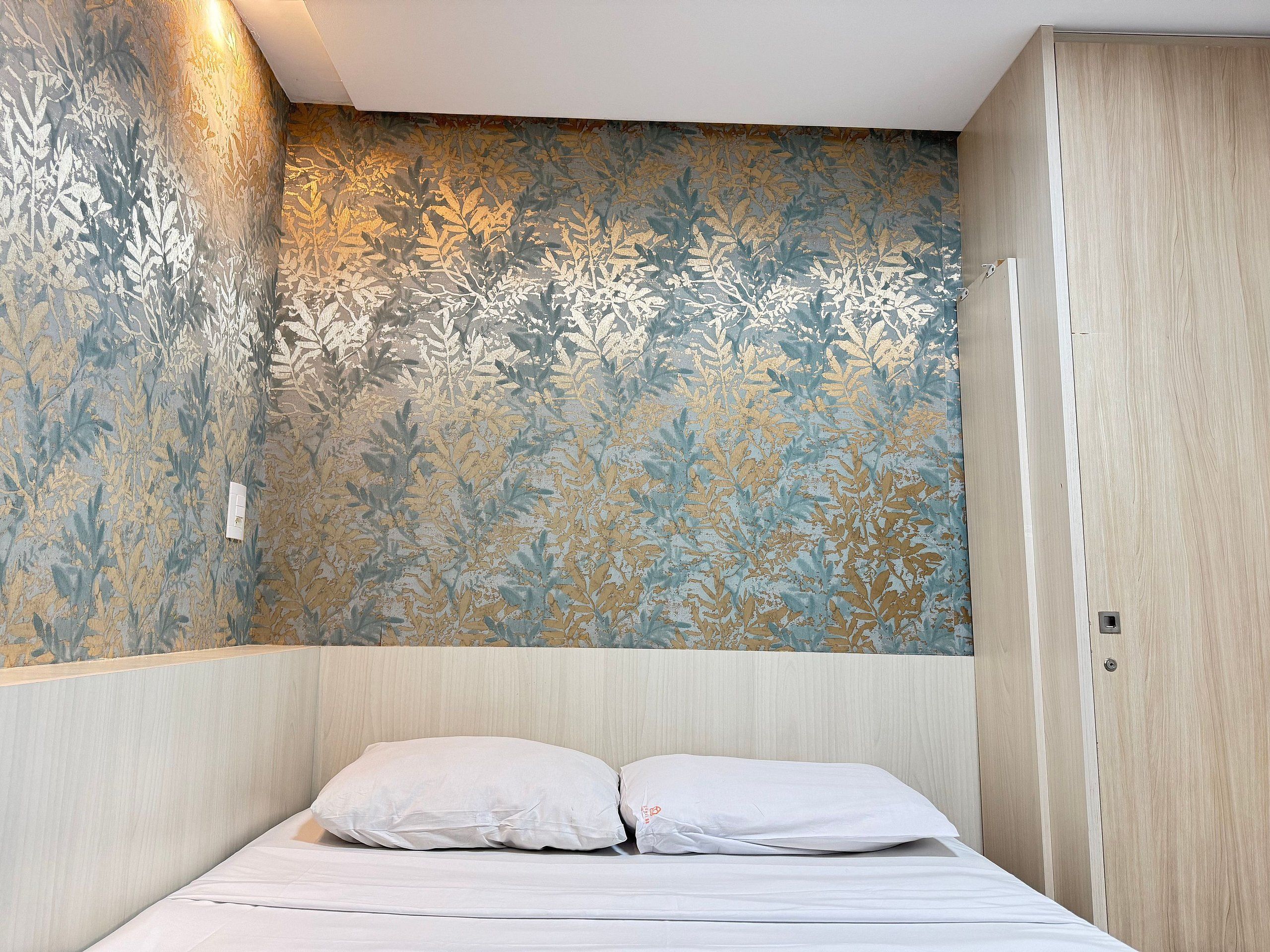 Una camera da letto con un letto, un armadio e una parete decorata con un motivo a foglia.