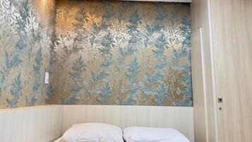 Una camera da letto con un letto, un armadio e una parete decorata con un motivo a foglia.