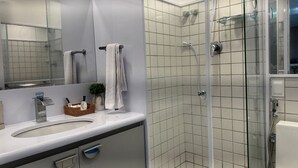 A modern bathroom with a glass-enclosed shower, a large mirror, and a white sink. - Nannai Residence Muro Alto Beira Mar (N. Sra. do Ó)