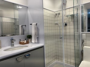 A modern bathroom with a glass-enclosed shower, a large mirror, and a white sink. - Nannai Residence Muro Alto Beira Mar (N. Sra. do Ó)