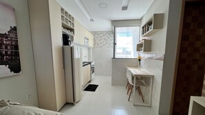 A modern kitchen with a refrigerator, stove, and microwave. There is a dining area with a table and chairs. - 305 2 Bedrooms 15 min from the Center (Belém)