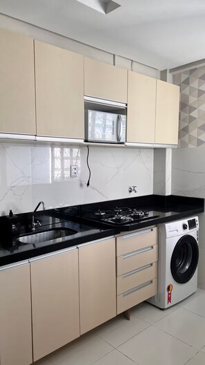 A modern kitchen with a built-in microwave, gas stove, and a washing machine. - 305 2 Bedrooms 15 min from the Center (Belém)