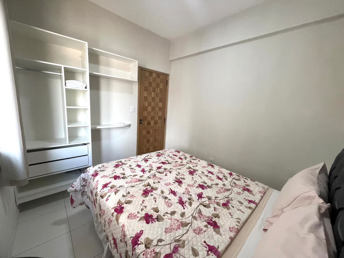 A bedroom with a bed, a wardrobe, and a door.