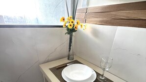 A dining area with a white table, a vase with yellow flowers, a wine glass, and a chair. - 305 2 Bedrooms 15 min from the Center (Belém)