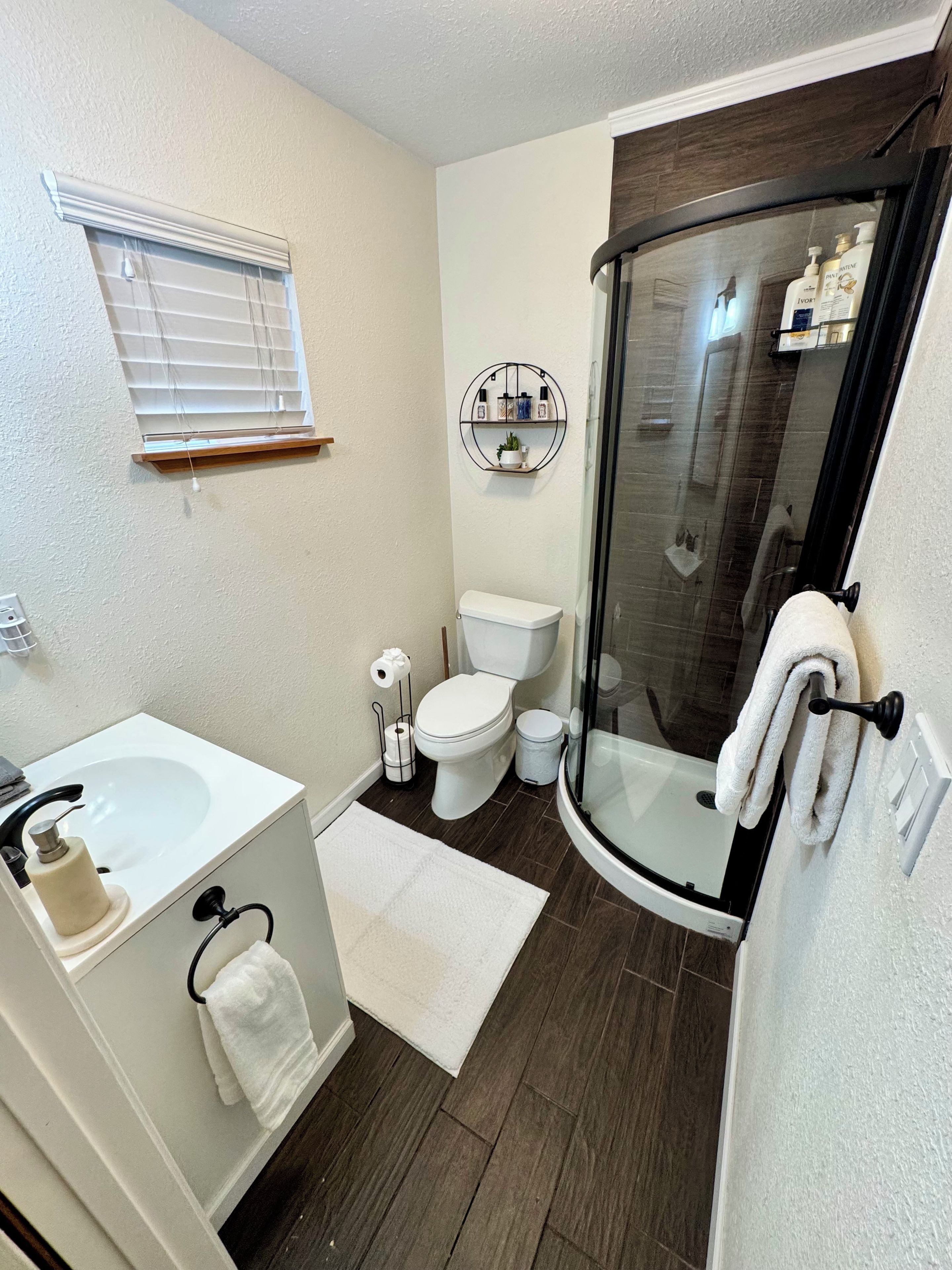 A bathroom with a toilet, sink, and shower.