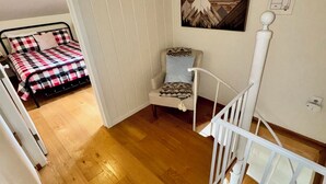 Um quarto com uma cama, uma cadeira, uma escada e um quadro na parede.