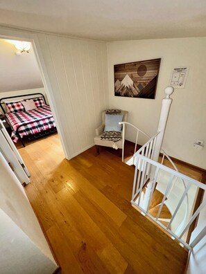 A bedroom with a bed, a chair, a staircase, and a painting on the wall. - Entire cabin in South Lake Tahoe, California (South Lake Tahoe)
