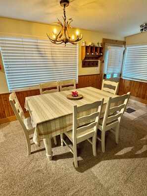 A dining room with a table, chairs, a chandelier, and a kitchen area with a refrigerator and cabinets. - Entire cabin in South Lake Tahoe, California (South Lake Tahoe)