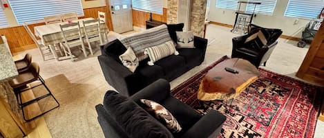 A cozy living room with a black sofa, a coffee table, and a patterned rug.