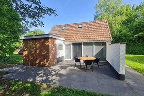 Una casa con patio, un cobertizo de madera y un área cercada.