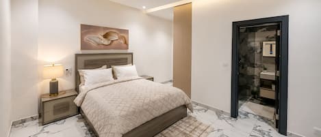 A bedroom with a bed, nightstands, a lamp, a painting, a mirror, and a bathroom door.