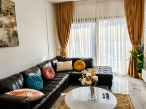 A modern living room with a leather sofa, a coffee table, and a vase of flowers. - 2-bedroom apartment in awesome Dakar with AC and fitness room Fast Wifi (Dakar)