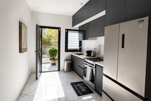 A modern kitchen with a built-in oven, a stainless steel refrigerator, and a window overlooking a garden. - 2-bedroom apartment in awesome Dakar with AC and fitness room Fast Wifi (Dakar)