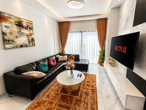 Un soggiorno moderno con un divano in pelle, un tavolino da caffè e una televisione a schermo piatto che mostra 'NETFLIX'.