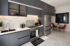 Una cucina moderna con mobili grigi, un frigorifero in acciaio inossidabile, un piano cottura a gas e un angolo caffè.