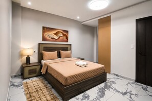 Un dormitorio moderno con cama, mesita de noche, lámpara y una obra de arte en la pared.