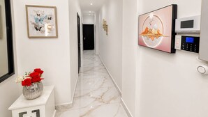 Un passadís amb sòl de marbre, un ram de flors vermelles i blanques, una obra d'art emmarcada i un panell de seguretat fixat a la paret.