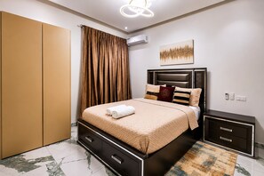 Une chambre moderne comprenant un lit, une armoire, une table de chevet et un climatiseur fixé au mur.