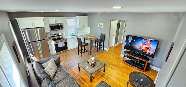 Um apartamento moderno com cozinha, sala de jantar, sala de estar e televisão.