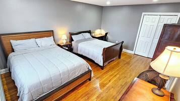 A bedroom with two beds, a desk, a chair, and a lamp.