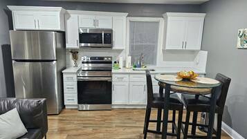 A modern kitchen with white cabinets, stainless steel appliances, and a dining area with a round table and chairs.