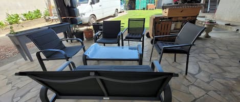An outdoor patio with stone flooring, a white van, and a barbecue grill.