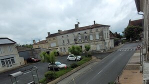 A street view with a building, parked cars, and a pedestrian crossing. - LE CLOS DES VOYAGEURS Bed and Breakfast ALL THE COMFORTS (Saint-Christophe-de-Double)