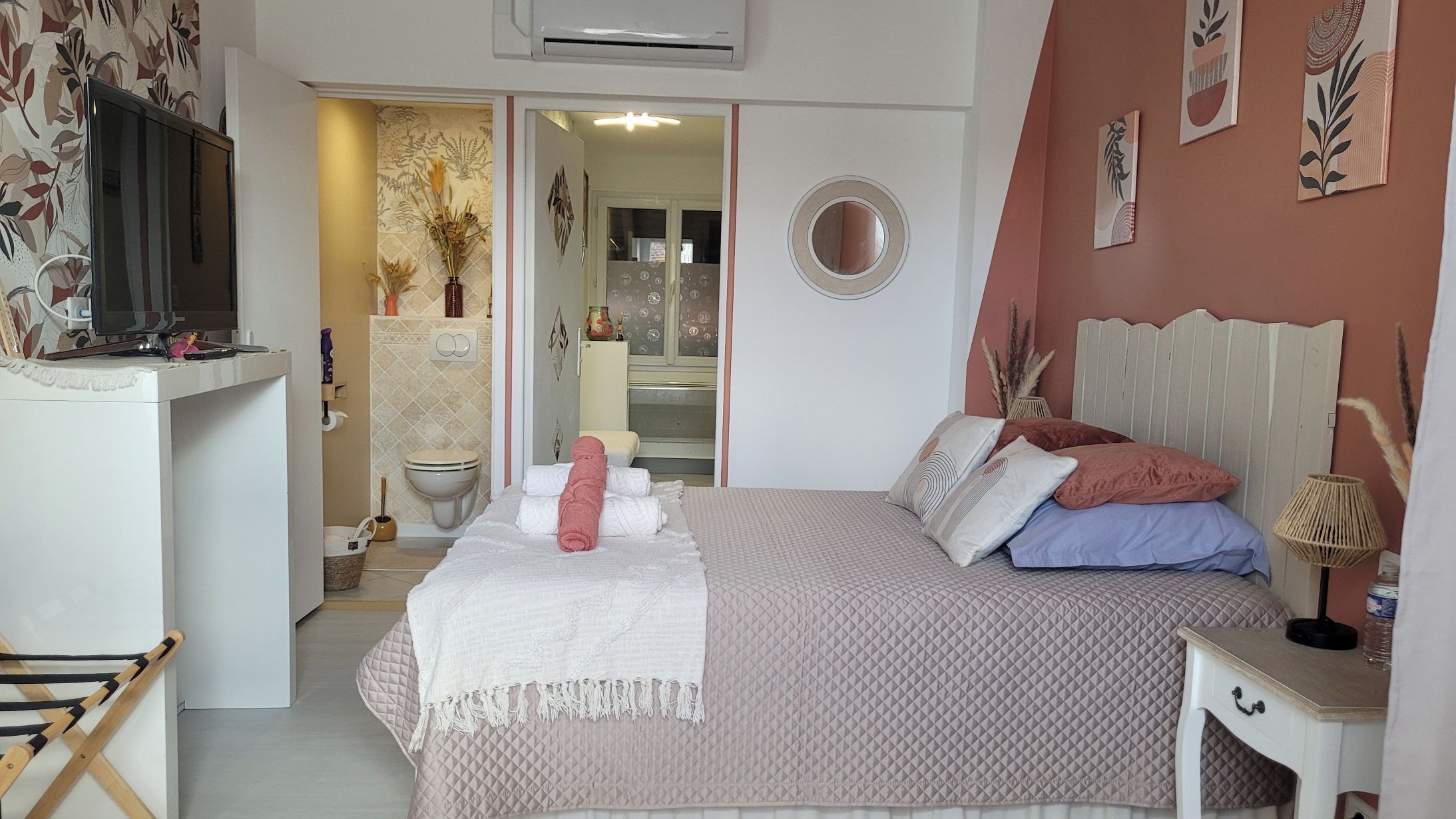 Een slaapkamer met een bed, nachtkastje en een televisie op een standaard.